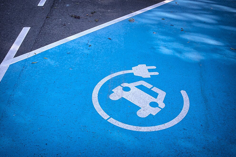 Eine blaue Parkfläche mit einem E-Auto Symbol darauf.