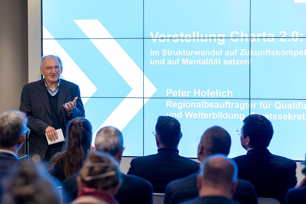 Peter Hofelich steht vor einer Leinwand auf der die Charta 2.0 der WBV vorgestellt wird