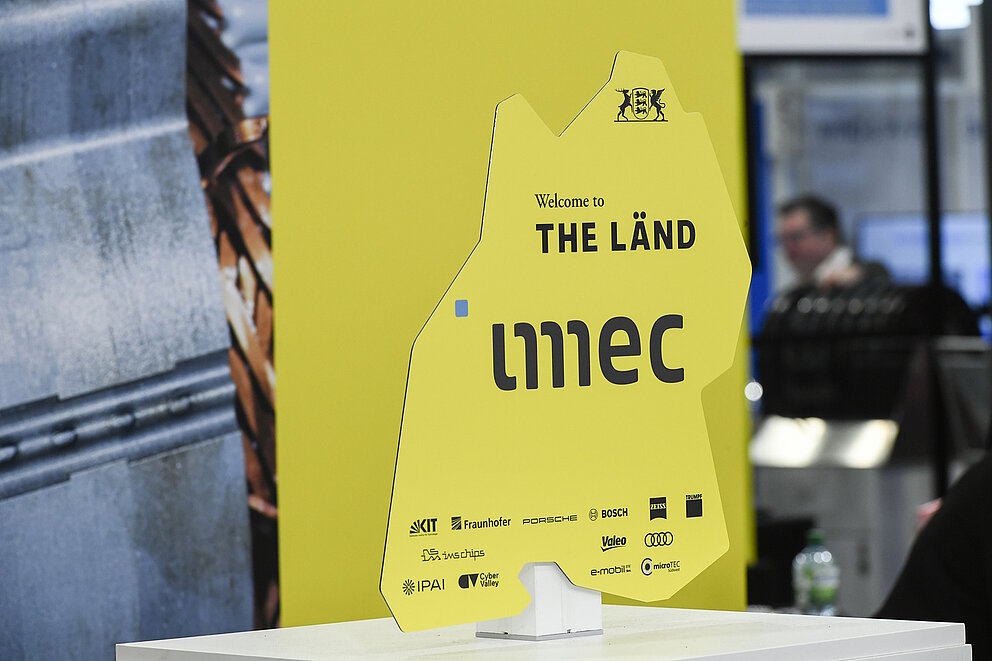 Ein gelbes Schild in Form des Bundeslandes Baden-Würrtemberg heißt das imec in THE LÄND willkommen.