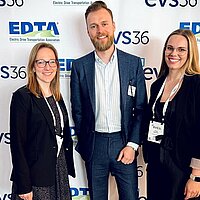 Katja Gicklhorn, Walter Holderried und Alina Richter stehen vor einer Fotowand mit der Aufschrift "EVS36"
