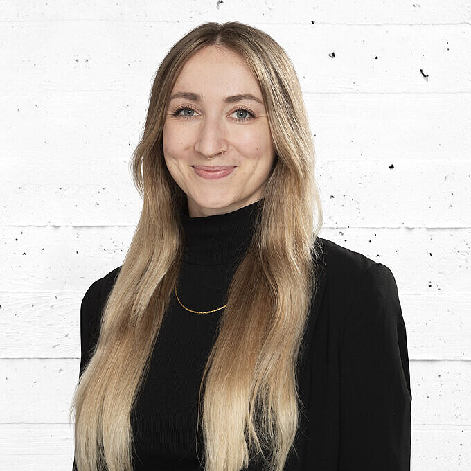 Portrait einer lächelnden Frau mit blondem Haar und schwarzem Blazer