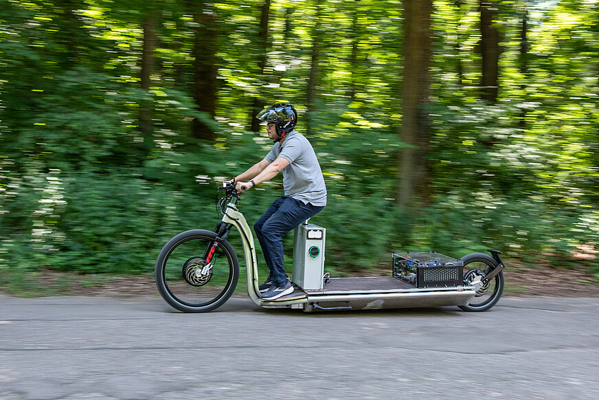 Eine Person fährt das elektrische Lastenkraftrad mit Schnellladefunktion der Universität Ulm.