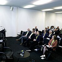 Die Wirtschaftsministerin Dr. Nicole Hoffmeister-Kraut eröffnet den Batterietag Cluster ESW. Im Publikum sitzen die Teilnehmenden.