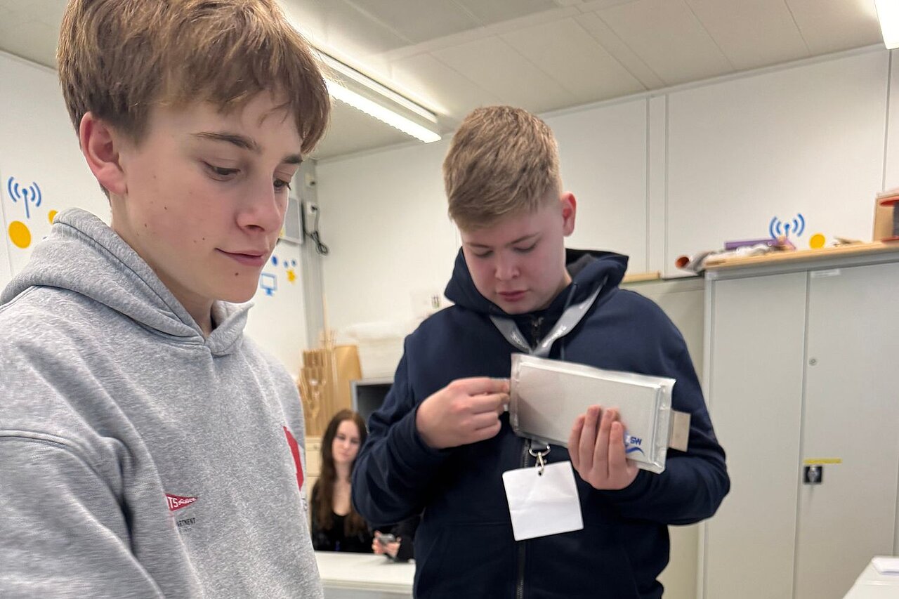 Nahaufnahme von zwei Jungen, die sich unterschiedliche Arten von Batterien ansehen.