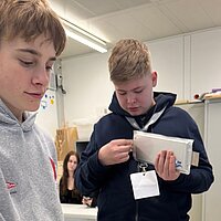 Nahaufnahme von zwei Jungen, die sich unterschiedliche Arten von Batterien ansehen.