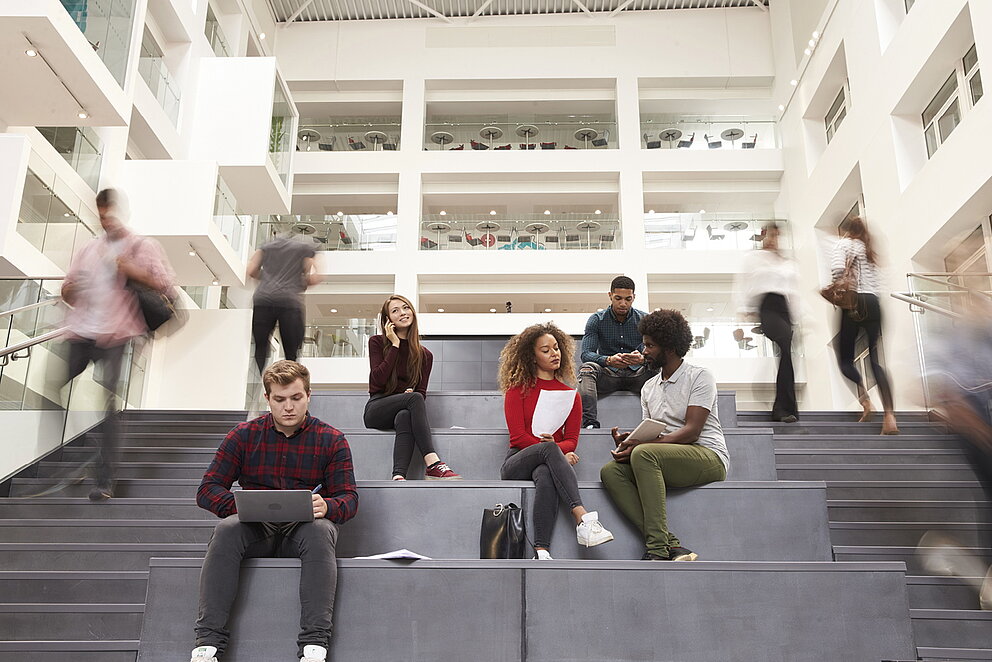 Junge Studierende sitzen auf den Treppenstufen eine Hochschule