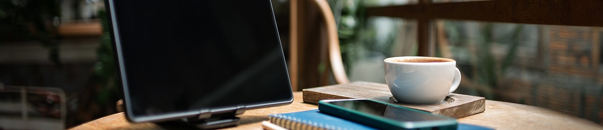 Arbeitsplatz Auf einem runden Tisch stehen ein Bildschirm, mehrere Bücher und eine Kaffeetasse.