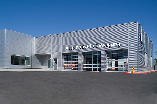 Autohaus mit silberner Außenfassade und Schriftzug "Automotive in Bewegung"