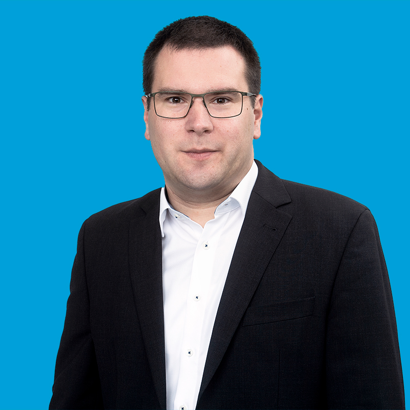Porträt von Stefan Büchele vor blauem Hintergrund